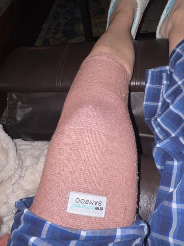 Customer wearing the pink Premium Bamboo Knee Sleeve on their leg while resting at home.