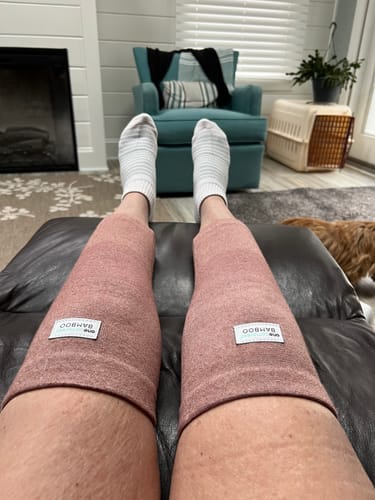 Customer wearing a pair of pink Premium Bamboo Knee Sleeves while resting indoors.