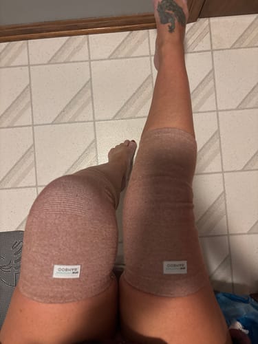 A customer wearing a pair of heathered brown Premium Bamboo Knee Sleeves on both knees.