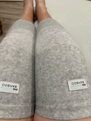 Reviewer wearing a pair of light grey Premium Bamboo Knee Sleeves on both knees while resting their legs.